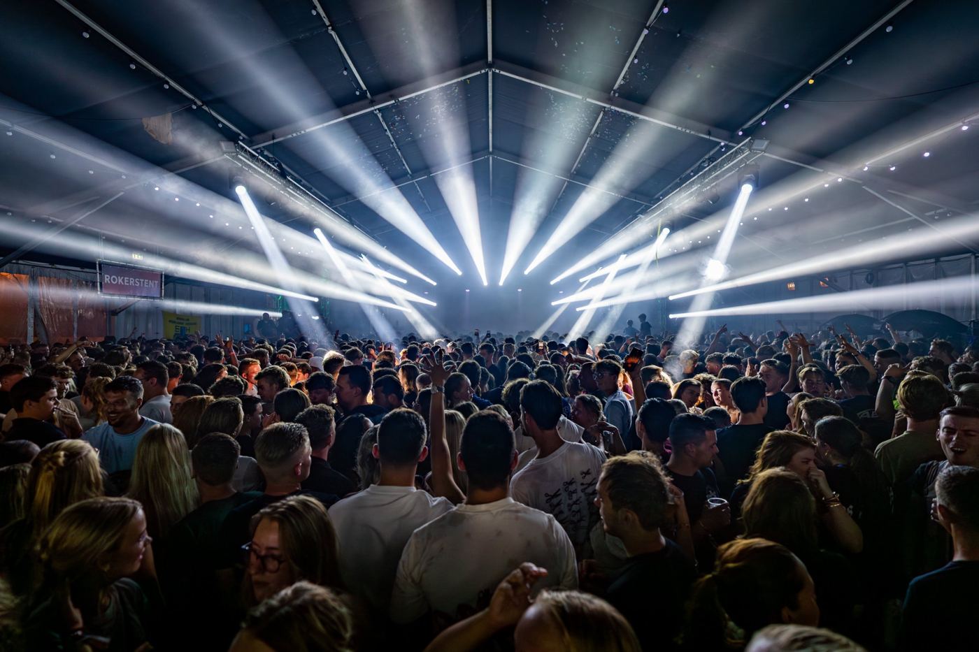 Symmetrische lichtshow met witte beams in een feesttent
