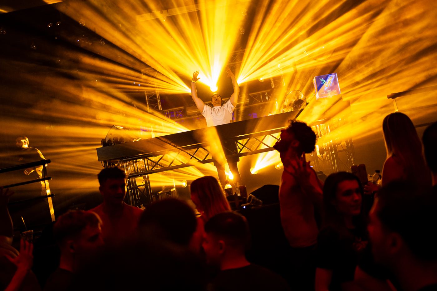DJ op het podium omringd door gele lichtbundels